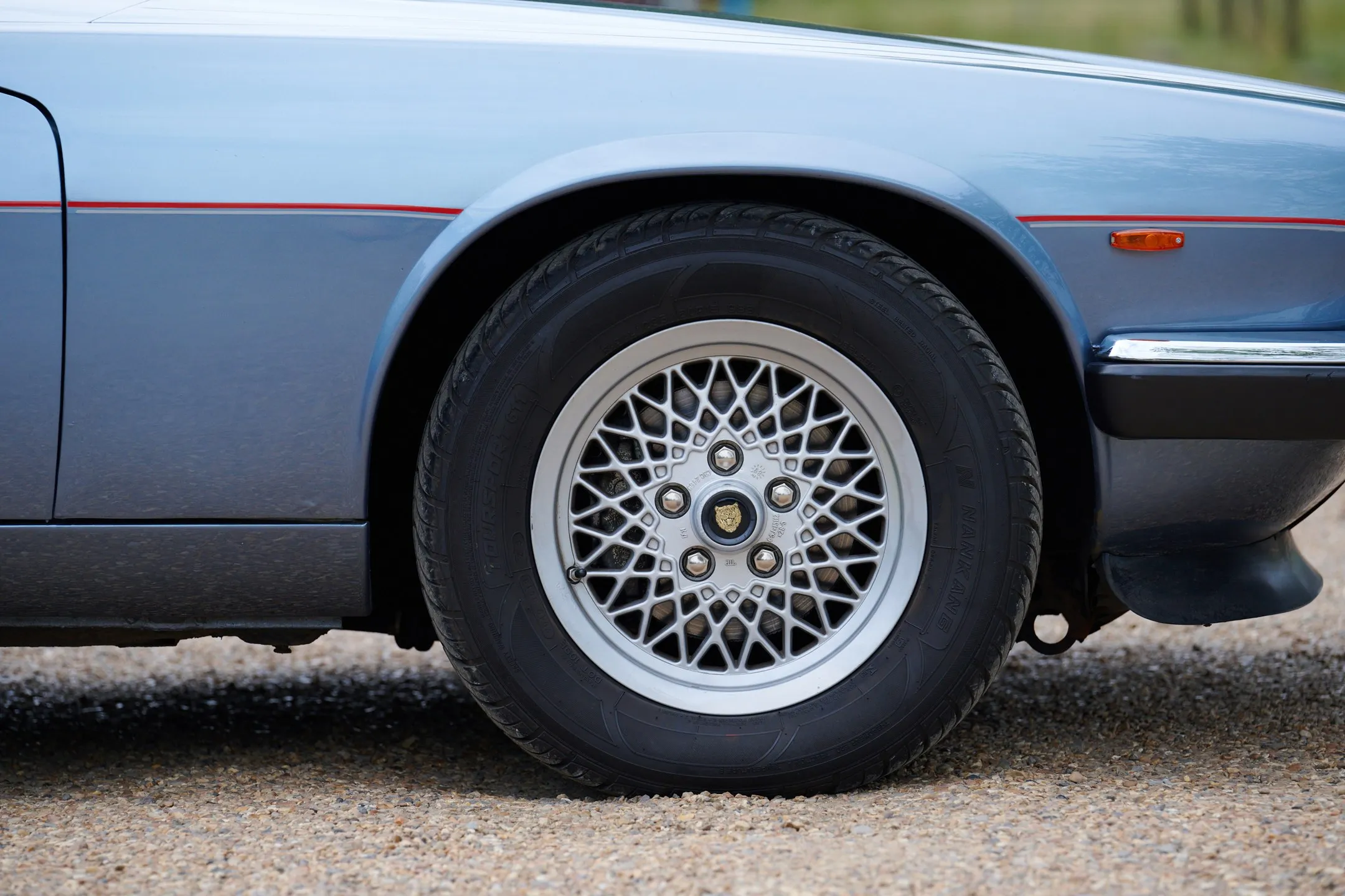 Detail of the XJ-S: fifteen-inch alloy wheel and the red and silver pinstripe